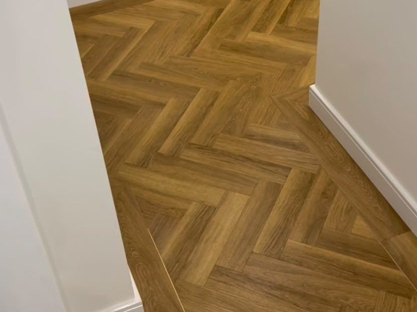 Detail van een strak gelegde vloer met een nette aansluiting langs de wand