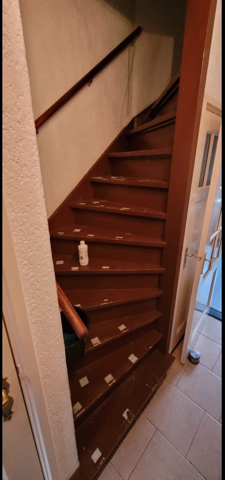 Gedraaide trap voor de renovatie, met donker gelakte houten treden