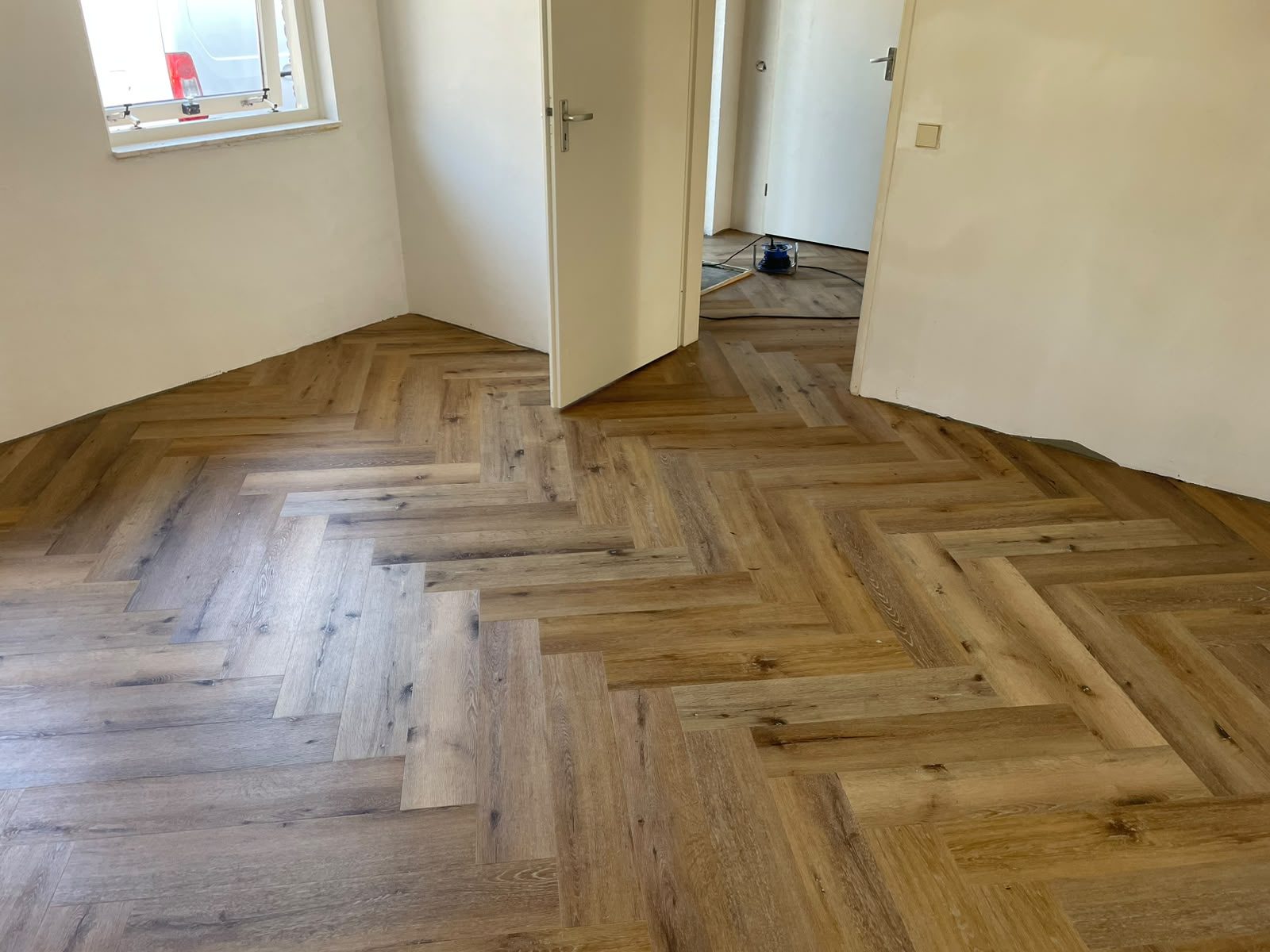 Warm eiken PVC visgraatvloer in de woonkamer met doorkijk naar de hal