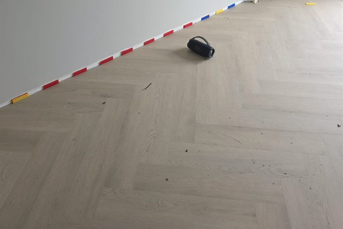 Gietvloerlaag onder een pas gelegde vloer, met uitzetruimte langs de wand