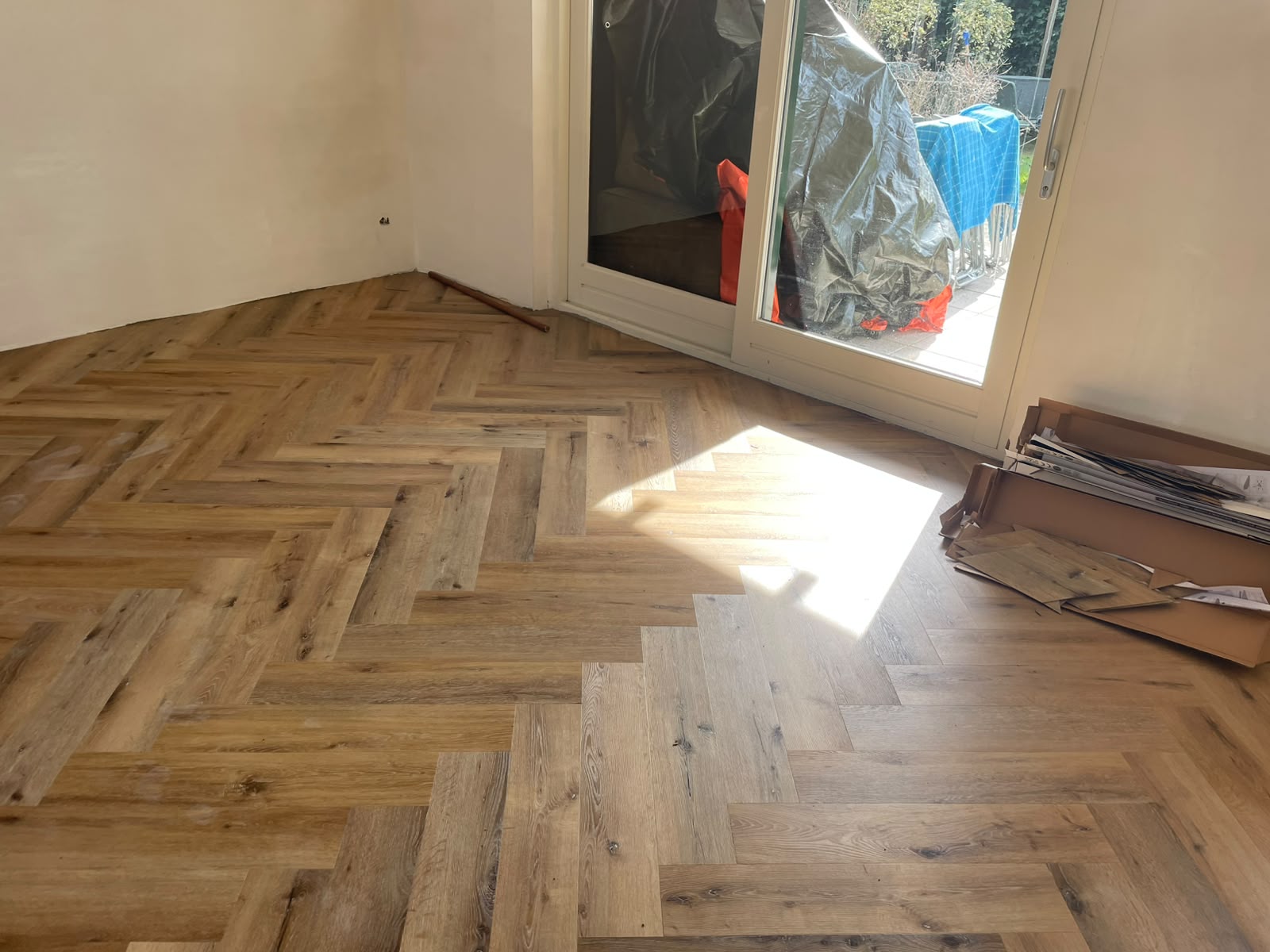 PVC visgraatvloer in eiken met strijklicht door het raam, gelegd in een woonkamer